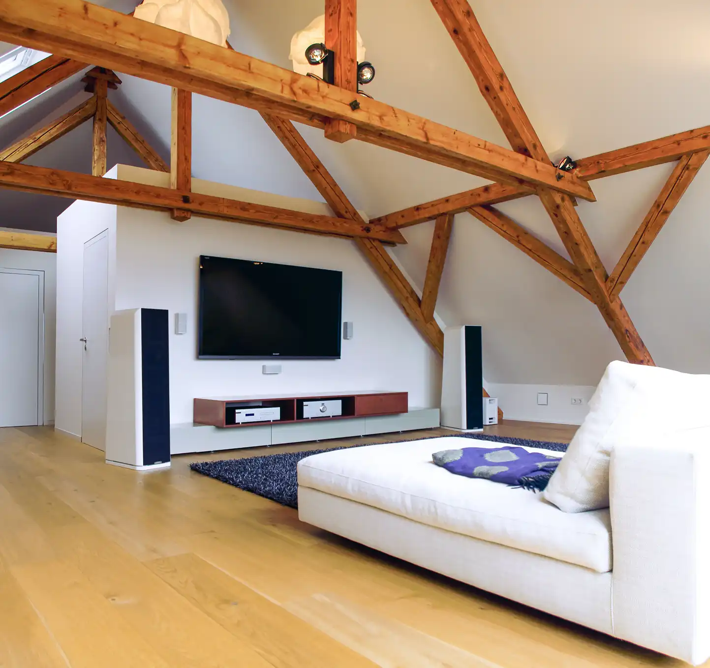 Wohnzimmer unter dem Dach mit freiliegendem Gebälk, Heimkino, Sofa und maßgefertigtem Sideboard