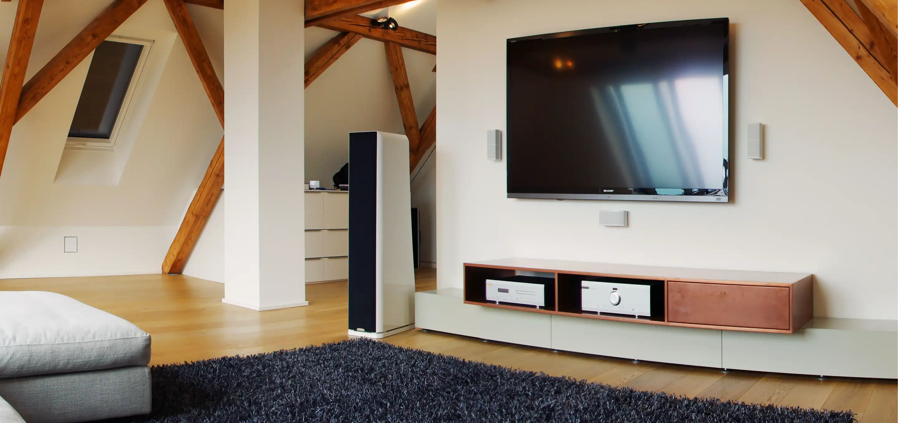 Wohnzimmer im Dachgeschoss mit Dachbalken und maßgefertigtem TV-Sideboard