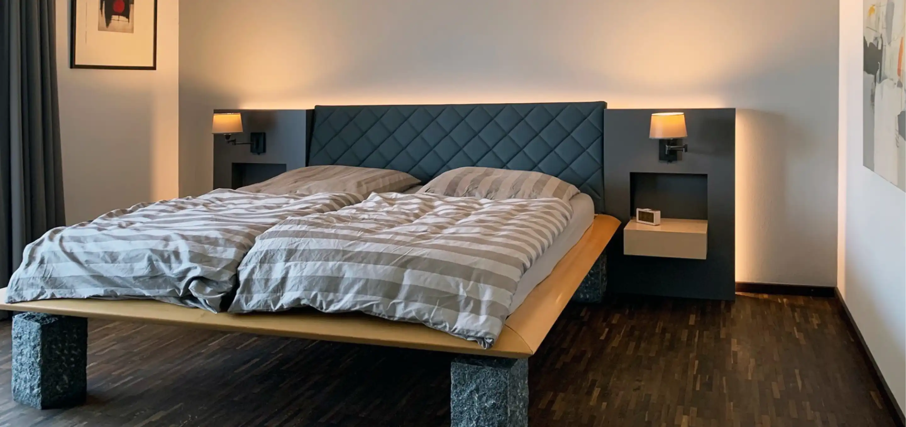 Schlafzimmer mit maßgefertigtem Bett, gesteppter Rückwand und Nachtkonsolen mit Wandleuchten