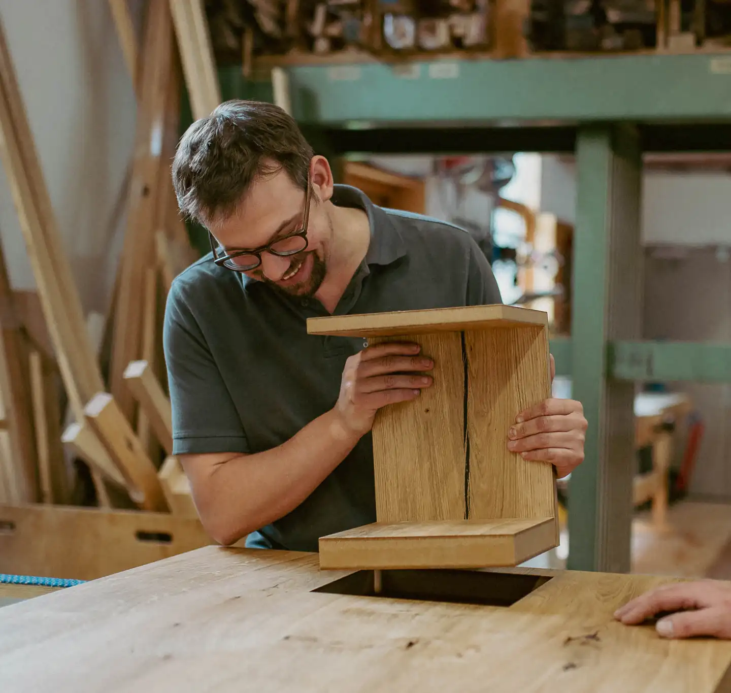 Schreiner in der Werkstatt prüft ein Werkstück aus Eiche